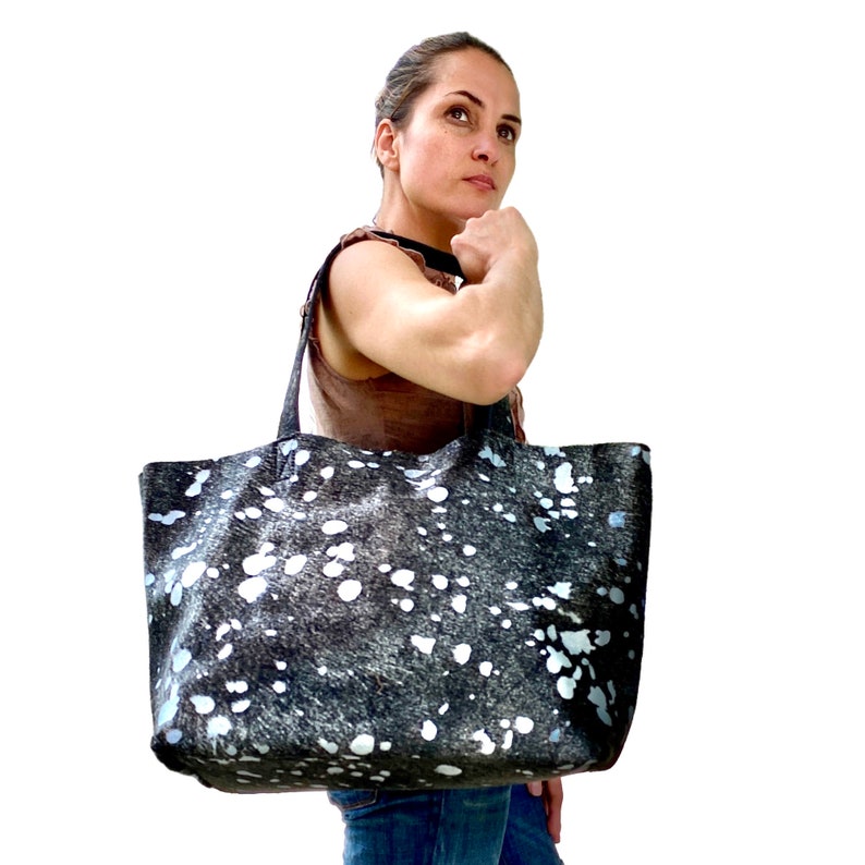 May include: A large black and white tote bag with a spotted pattern. The bag has two handles and is made of a soft, textured material.