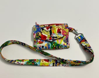 May include: A colorful, patterned crossbody bag featuring a Christmas-themed design with characters. The bag has a red zipper, a front pocket, and a matching strap with a metal clasp. The strap is approximately 40 inches long.