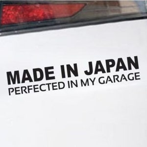 Puede incluir: Un coche blanco con una pegatina negra que dice "Made in Japan Perfected in my Garage".