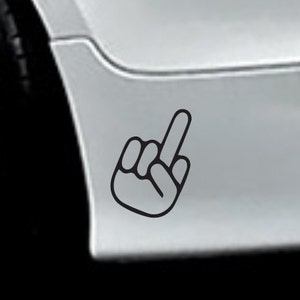 May include: A white car with a black middle finger sticker on the rear bumper.