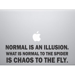 May include: A silver laptop with a black and white sticker that reads "NORMAL IS AN ILLUSION. WHAT IS NORMAL TO THE SPIDER IS CHAOS TO THE FLY."