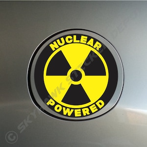 May include: A black and yellow round sticker with a nuclear symbol and the text "Nuclear Powered".
