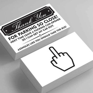 Op de afbeelding: Twee stapels witte visitekaartjes. De bovenste kaart in de eerste stapel heeft de tekst "Thank You" in een decoratief lettertype, gevolgd door een bericht over parkeren. De tweede stapel toont een zwarte omtrek van een hand die de middelvinger opsteekt.