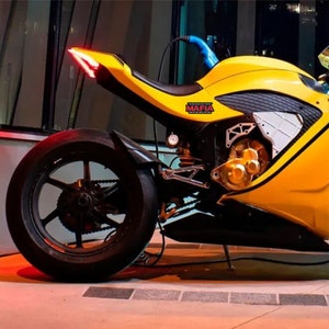 May include: A yellow electric motorcycle with a black seat and black wheels. The motorcycle has a black and white patterned design on the side and a red taillight. The motorcycle has a sticker that says "You don't want the MAFIA you'll be with us too long".