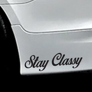 May include: A black and white car with the words "Stay Classy" written on the rear bumper.