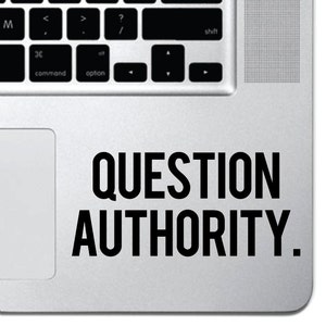 May include: A silver laptop with a black trackpad and a black sticker that says "QUESTION AUTHORITY."