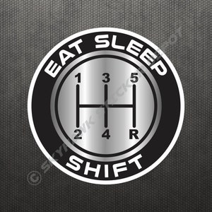 Op de afbeelding: Zwarte en witte ronde sticker met een zilveren schakelpatroon in het midden. De tekst "EAT SLEEP SHIFT" staat rond het schakelpatroon.