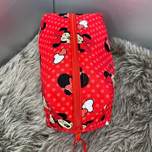 Op de afbeelding: Rode ritszak met een stippenpatroon en een Minnie Mouse-print. De tas heeft een rode rits.