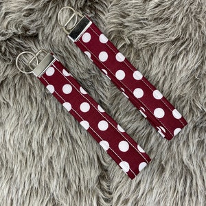 May include: Two burgundy keychains with white polka dots and silver key rings.