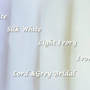 K&ouml;nnte beinhalten: Nahaufnahme von f&uuml;nf Stoffmustern in verschiedenen Wei&szlig;- und Elfenbeint&ouml;nen. Die Muster sind mit "Wei&szlig;", "Seidenwei&szlig;", "Hell Elfenbein", "Elfenbein" und "Lord & Grey Bridal" beschriftet.