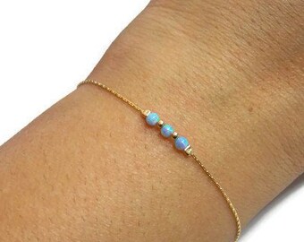 May include: A delicate gold chain bracelet with three small blue opal beads.