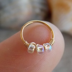 Può includere: Orecchino a cerchio dorato con tre perline iridescenti.