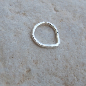 May include: A silver ring with a hammered finish. The ring is open and has a slightly irregular shape.