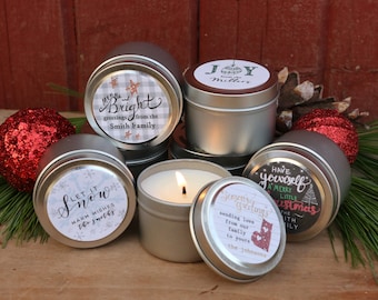 May include: Six silver candle tins with festive holiday labels. The labels feature various Christmas greetings, including "Let it Snow", "Merry and Bright", "Have Yourself a Merry Little Christmas", and "Season's Greetings".