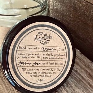 May include: A 9 ounce candle jar with a brown label that reads "NatureWorks" and "Hand-poured in Wisconsin". The label also states that the candle is made with American grown soy & local beeswax, cotton & paper wicks, ethically produced pure essential oils, and contains no artificial fragrance, dyes, paraffin, phthalates, or petro-carbon soot.