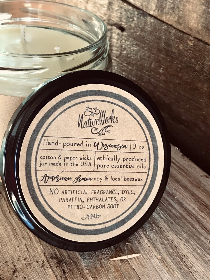 May include: A 9 ounce candle jar with a brown label that reads "NatureWorks" and "Hand-poured in Wisconsin". The label also states that the candle is made with American grown soy & local beeswax, cotton & paper wicks, ethically produced pure essential oils, and contains no artificial fragrance, dyes, paraffin, phthalates, or petro-carbon soot.