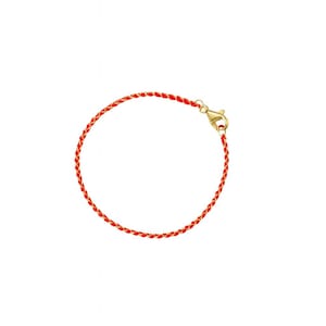 May include: A red braided bracelet with a gold-colored clasp. The bracelet is a simple, elegant design, perfect for everyday wear. The bracelet is approximately 7 inches in length.