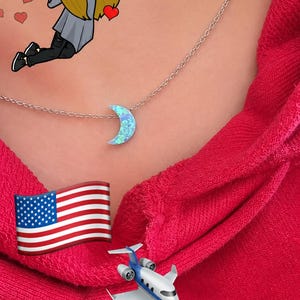 Close-up lifestyle photo of a woman wearing a dainty moon opal necklace on a delicate chain with a bright pink hoodie, featuring a dreamy playful travel-inspired aesthetic. lucky charms usa