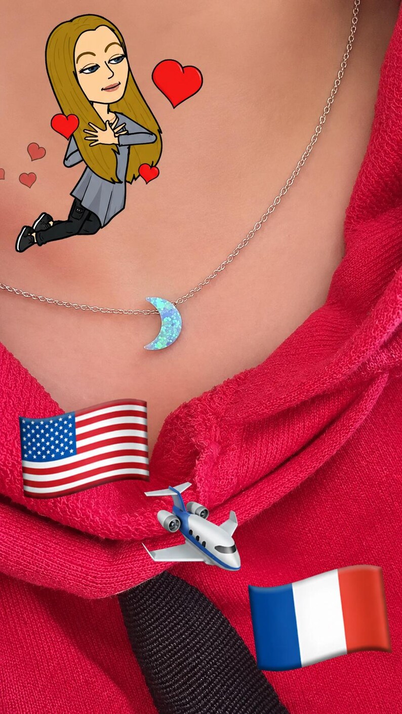Close-up lifestyle photo of a woman wearing a dainty moon opal necklace on a delicate chain with a bright pink hoodie, featuring a dreamy playful travel-inspired aesthetic. lucky charms usa