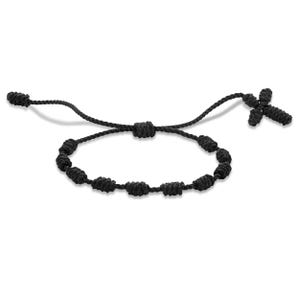 May include: Black knotted bracelet with a cross charm. The bracelet features a series of evenly spaced knots forming a loop, with a cross-shaped charm at one end. The adjustable design allows for a comfortable fit. The bracelet is made of a dark, possibly nylon, material.
