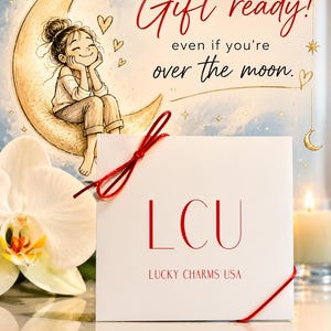 Gift ready jewelry packaging photo featuring Lucky Charms USA necklace card styled with a dreamy illustrated moon background, delicate hand-drawn details, soft candlelight, orchid accents, and the phrase “Gift ready! even if you’re over the moon.”