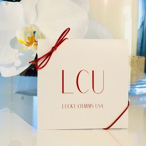 Lucky Charms USA Beautiful Jewelry Package in White, and Red Colors and with a Red Ribbon and A Blessing Card That Reads: May You Be Protected, Happy, Healthy And Wealthy.