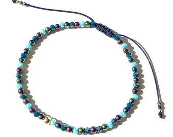 Beadazzled bracelet with crystal gems and iridescent hematite beads with gold ball surprise on blue cord