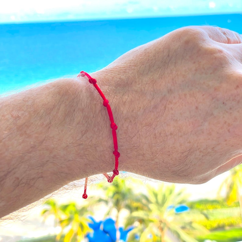 handmade shiny red string bracelet with 7 handmade knots for women men kids babies in adjustable custom-made wrist sizes, handmade-red-7 knot-string-bracelet-gift made to order in USA by Lucky Charms USA