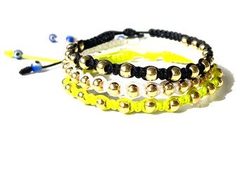 Beaded bracelets in gold-filled balls and black white and neon green color strings with evil eye beads in Limited edition