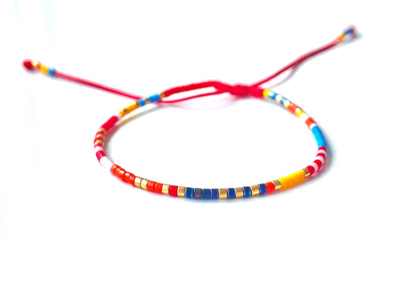 miyuki seed bead Delica bracelet in red, yellow, black, gold, white, light blue, color beads, on adjustable red string waterproof bracelet handmade to order in USA by Lucky Charms USA