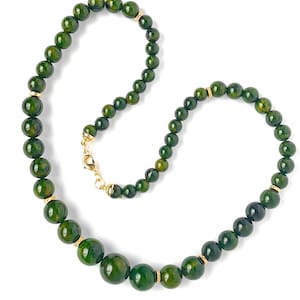 May include: A beaded necklace featuring round, dark forest green beads with subtle mottled patterns. The beads are interspersed with small, textured gold-toned metal spacers and finished with a gold-toned lobster claw clasp closure.