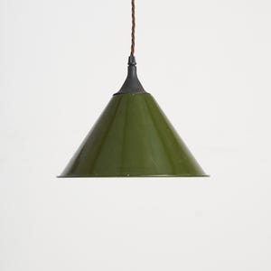 May include: Olive green pendant light with a conical shade. The light fixture has a dark metal base and a brown cord. The shade is a solid, matte olive green colour. The light hangs from the ceiling.
