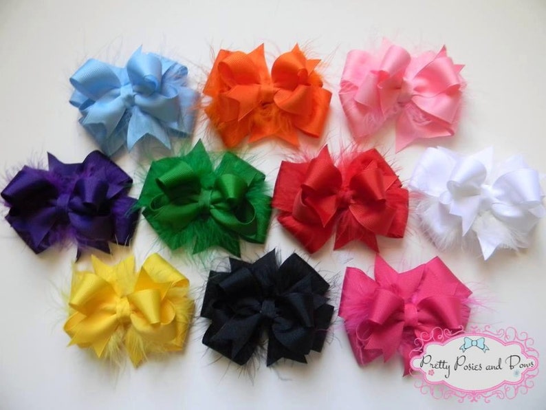 Op de afbeelding: Tien verschillende gekleurde haarbandjes met verenversiering. De strikken zijn gemaakt van satijnen lint en zijn in een dubbele lus geknoopt. De kleuren zijn paars, groen, blauw, oranje, roze, rood, wit, geel, zwart en felroze.