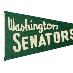 May include: Green felt pennant with the words "Washington SENATORS" in white, with a white star. The pennant is triangular and has a white border. The text is in a vintage, slightly distressed font.