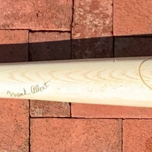 May include: A wooden Louisville Slugger baseball bat with signatures from various players, including "Johnny Bench" and "Charlie Hustle". The bat is signed with a black marker and has a white sticker with the text "Don Drysdale 1962" on the side.