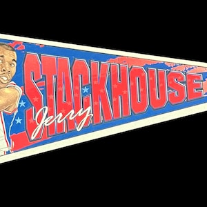 May include: A vintage pennant featuring a basketball player in a blue and red jersey with the number 42. The pennant is blue and red with white stars and the text "Jerry Stackhouse 42" in red.