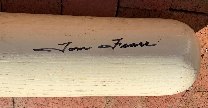 May include: White wooden baseball bat with black ink signature "Tom Seaver" on the surface.