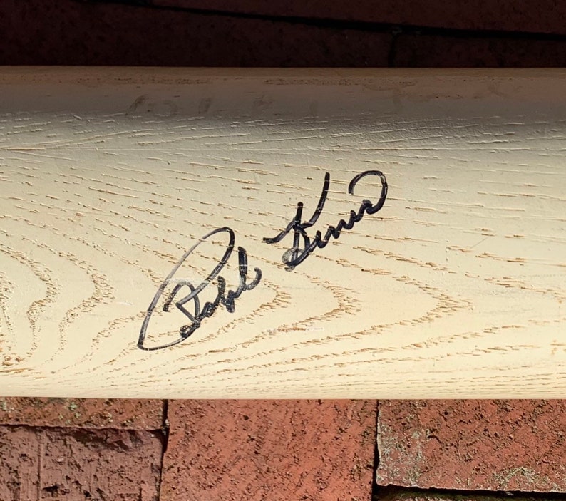 May include: A white wooden baseball bat with a black signature that reads "Bobbi Brown".