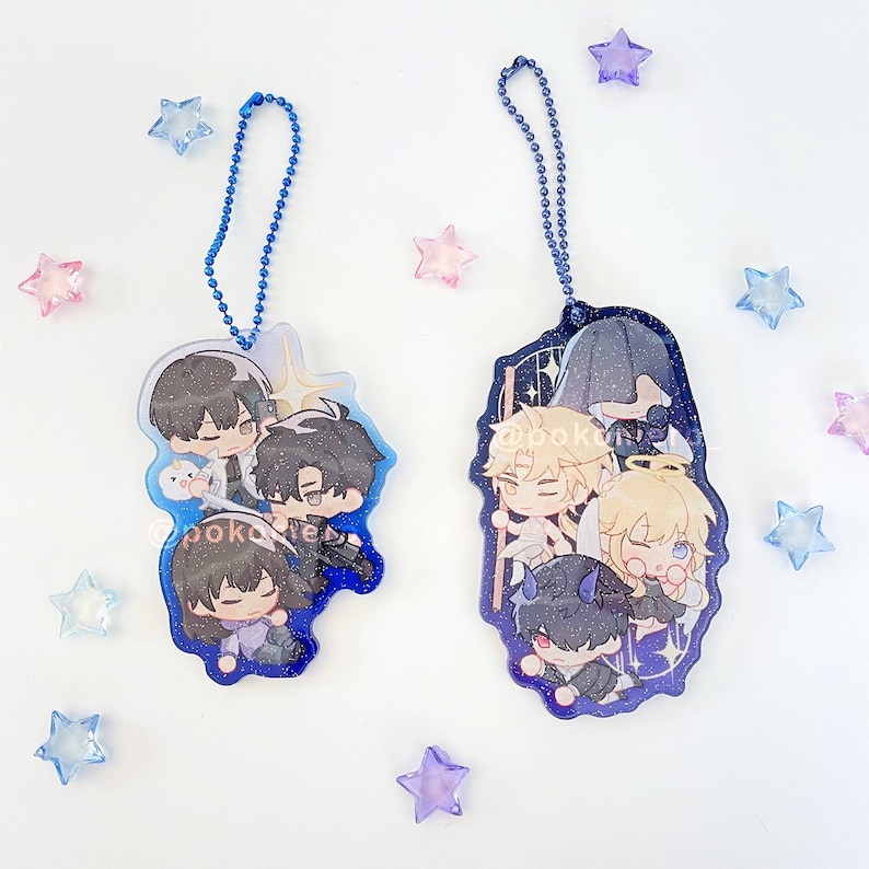Puede incluir: Dos llaveros con dijes de personajes azules y blancos con cadenas plateadas. Los dijes representan personajes de estilo anime con cabello y ropa de diferentes colores. Los personajes est&aacute;n sobre un fondo estrellado azul y blanco.