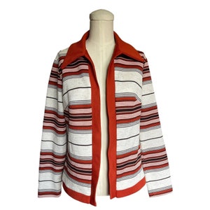 May include: A striped cardigan with a rust-colored collar and front panel. The cardigan has a white background with rust, brown, and pink stripes.