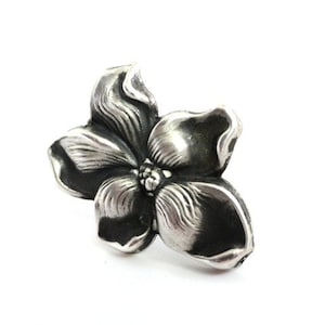 Puede incluir: Un anillo de plata con forma de flor con un dise&ntilde;o detallado. La flor tiene cinco p&eacute;talos y un centro con un peque&ntilde;o detalle en relieve.
