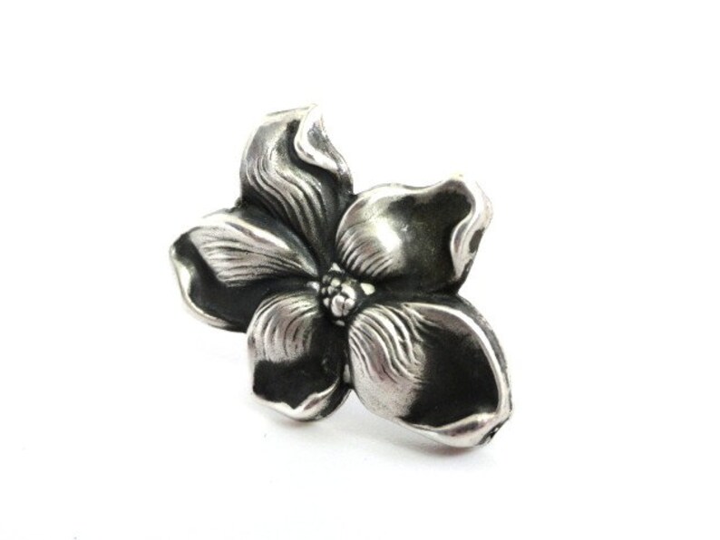 Puede incluir: Un anillo de plata con forma de flor con un dise&ntilde;o detallado. La flor tiene cinco p&eacute;talos y un centro con un peque&ntilde;o detalle en relieve.
