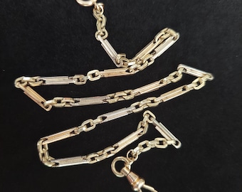 May include: A gold pocket watch chain with a double row of links. The chain has a swivel clasp and a T-bar.