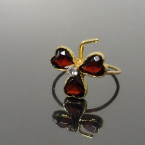 May include: A gold ring with three red heart-shaped stones and a single clear stone in the center.
