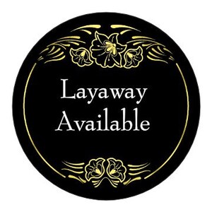 May include: Black and gold circular sign with a decorative floral border. The sign reads "Layaway Available" in white text.