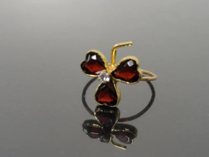 May include: A gold ring with three red heart-shaped stones and a single clear stone in the center.
