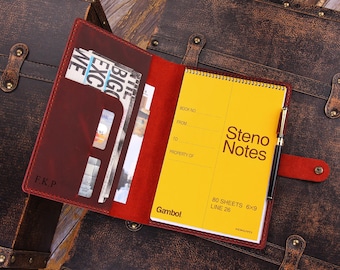 May include: A red leather notebook with a yellow notepad inside. The notepad has the words "Steno Notes" printed on the front. The notebook has a pen holder and a pocket for cards and other items.