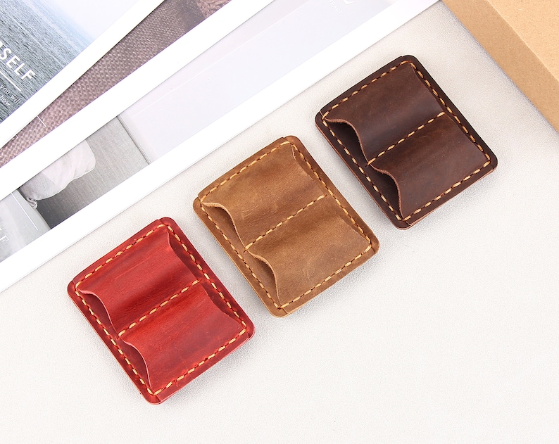 May include: Three leather pouches with two compartments each. The pouches are brown, tan, and red.