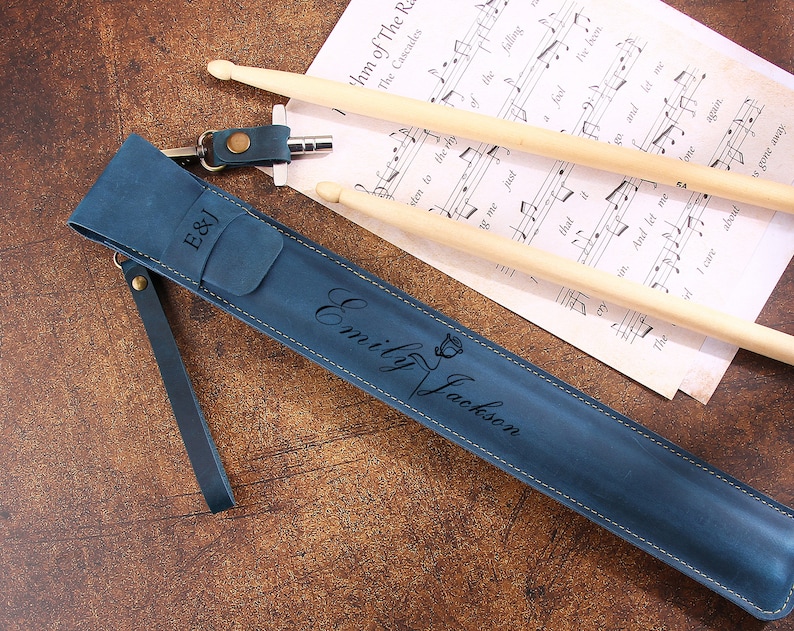 Peut inclure: Un &eacute;tui &agrave; baguettes en cuir bleu avec une inscription personnalis&eacute;e qui dit "E&J Emily Jackson". L'&eacute;tui a une sangle et un petit charme en m&eacute;tal attach&eacute;.