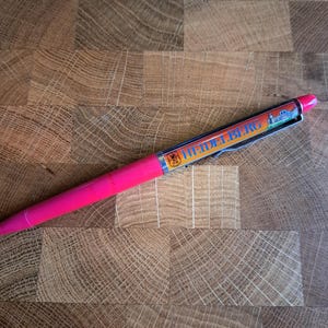 Op de afbeelding: Een roze pen met een wit en blauw ontwerp met het woord "HEIDELBERG" en een afbeelding van een kasteel.